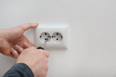 Electrician repairing wall sockets on white background, closeup. Space for text