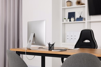 Photo of Stylish director's workspace with computer and stationery on desk in office. Interior design