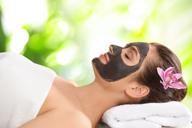 Image of Beautiful woman with black mask on face. Spa treatment