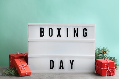 Lightbox with phrase BOXING DAY and Christmas decorations on grey table