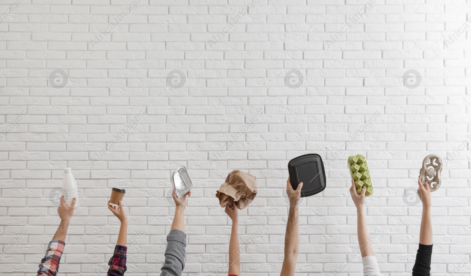 Photo of People holding different garbage against brick wall. Waste recycling concept