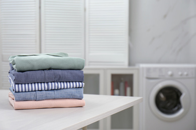 Photo of Fresh laundry on white wooden table in bathroom. Space for text