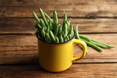 Photo of Fresh green beans in mug on wooden table