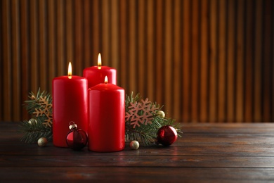 Photo of Beautiful composition with candles and Christmas decor on wooden table. Space for text