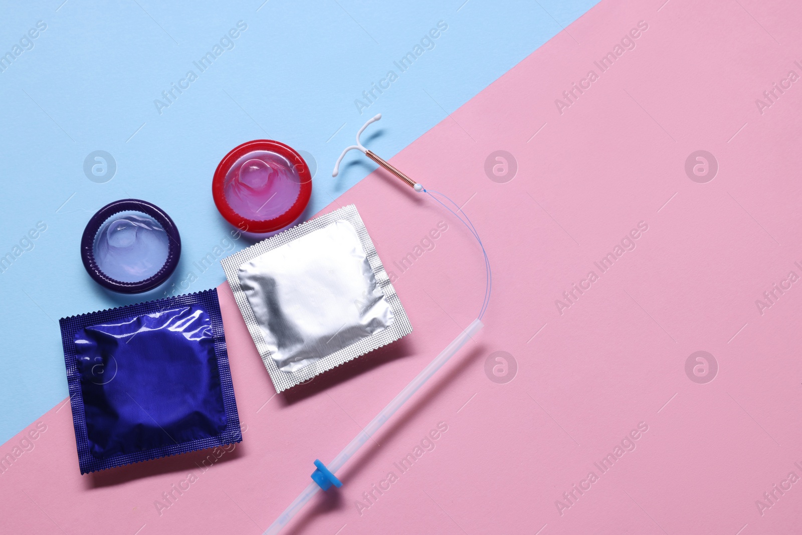 Photo of Condoms and intrauterine device on color background, flat lay and space for text. Choosing birth control method