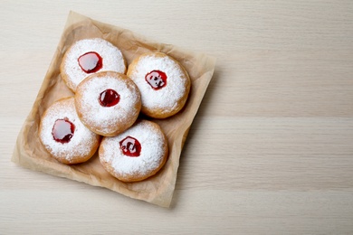 Photo of Hanukkah doughnuts with jelly and sugar powder served on wooden table, top view. Space for text