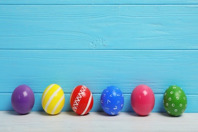 Photo of Decorated Easter eggs on table near wooden wall. Space for text