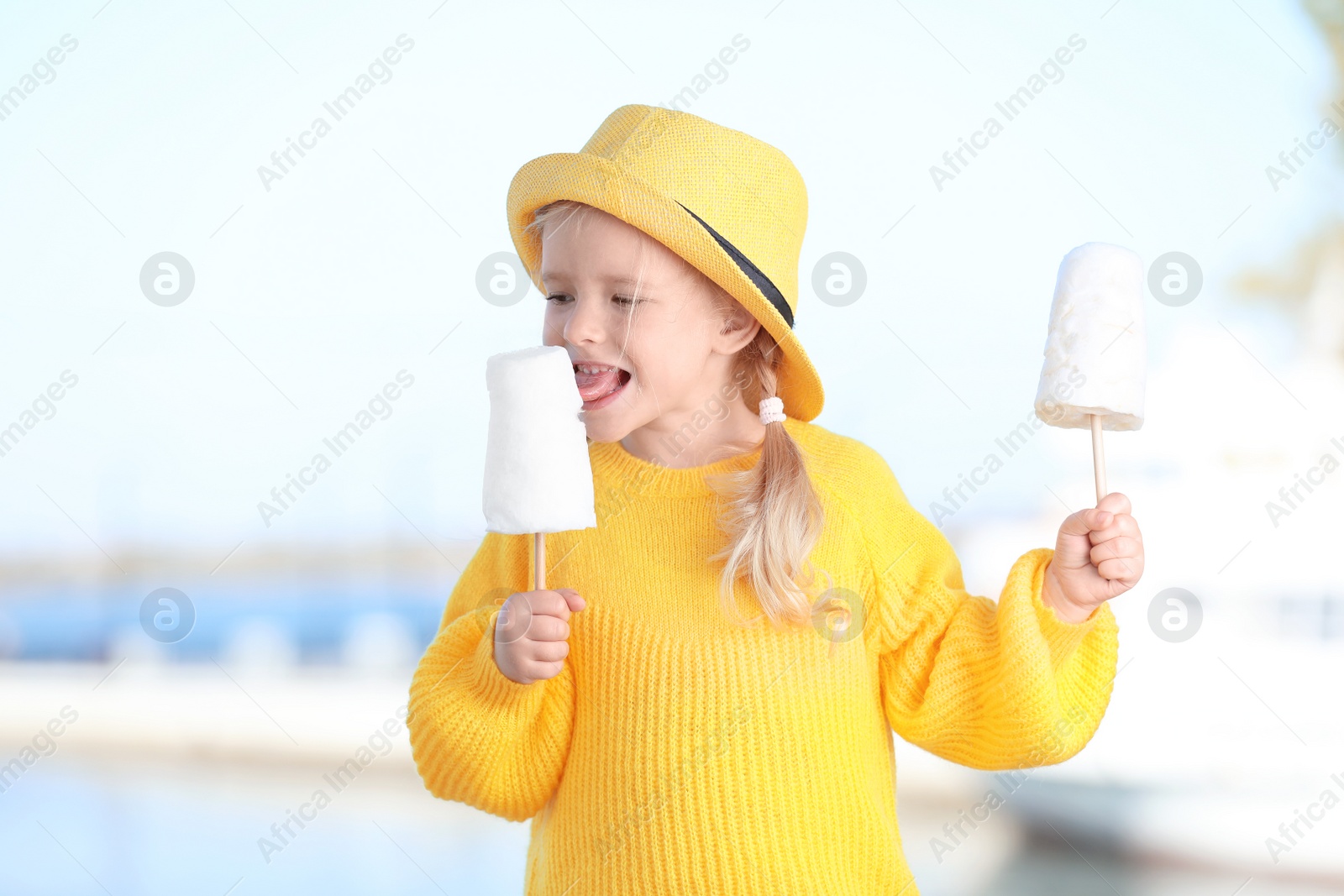 Photo of Cute little girl with cotton candies outdoors