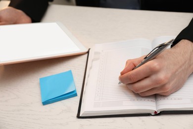 Photo of Man taking notes at white wooden table, closeup