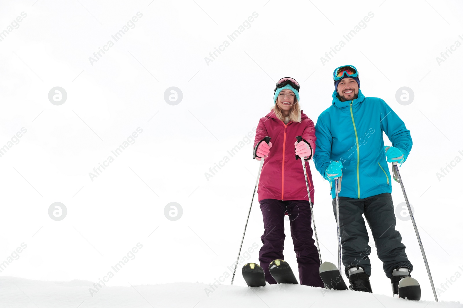 Photo of Couple of skiers on slope at resort, space for text. Winter vacation
