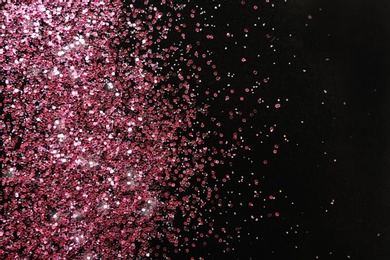 Photo of Rose gold glitter on black background, top view with space for text