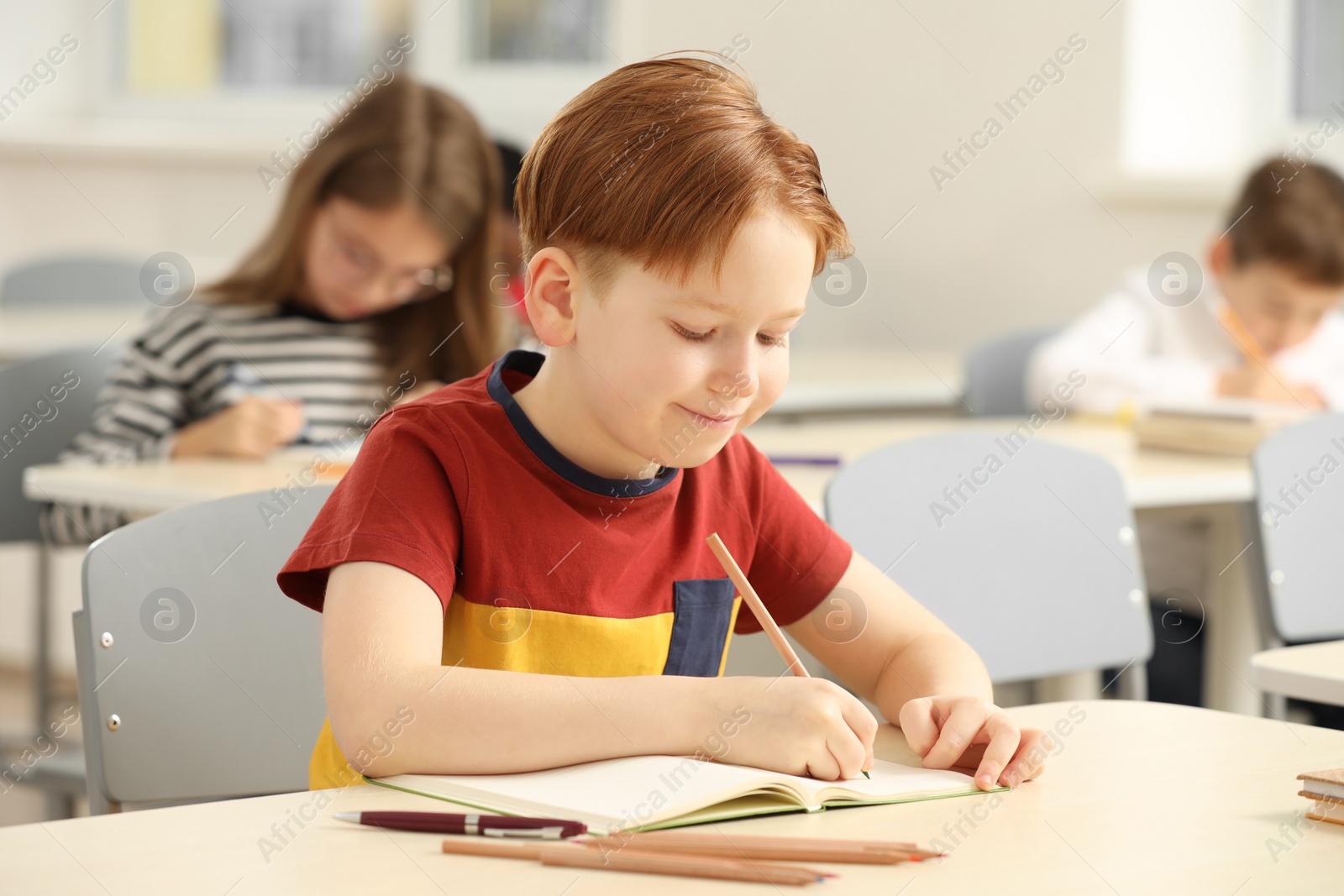 Photo of Cute little boy studying in classroom at school