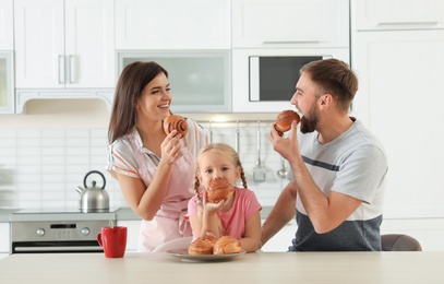 Photo of Happy family eating freshly oven baked buns in kitchen