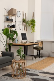 Cozy workplace with computer, modern furniture and houseplants at home