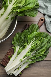Fresh green pak choy cabbage with water drops on wooden table, flat lay