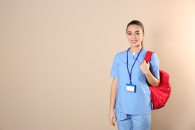 Young medical student with backpack on color background. Space for text