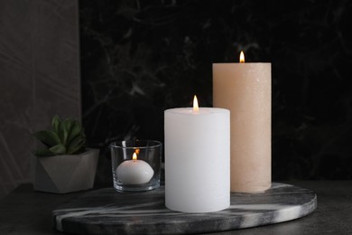 Marble board with burning candles on dark table