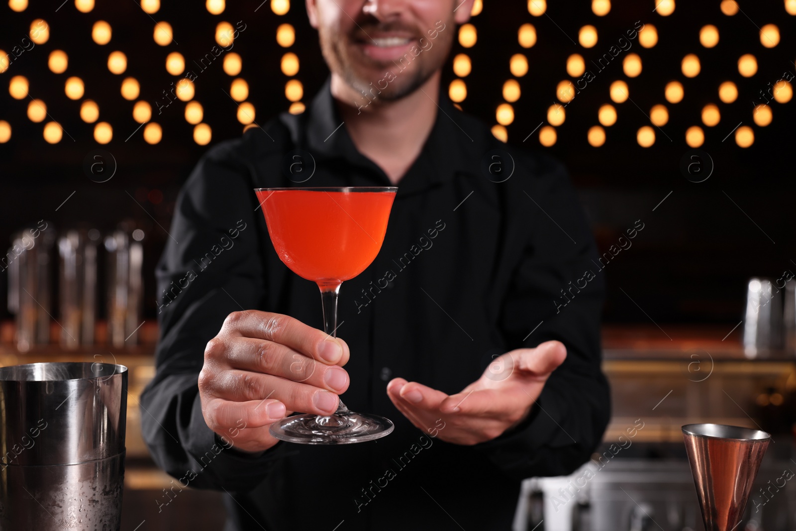 Photo of Bartender with fresh alcoholic cocktail in bar, closeup