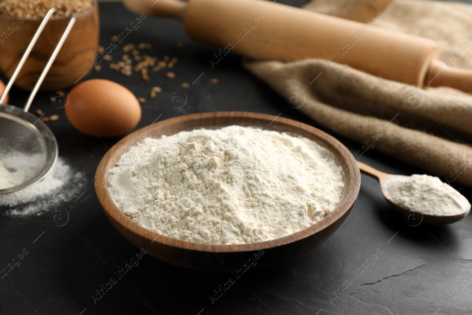 Photo of Wooden bowl of flour on black table