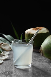Photo of Glass of fresh coconut water on table against dark background