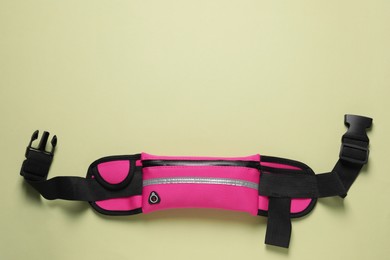 Photo of Stylish pink waist bag on pale green background, top view. Space for text