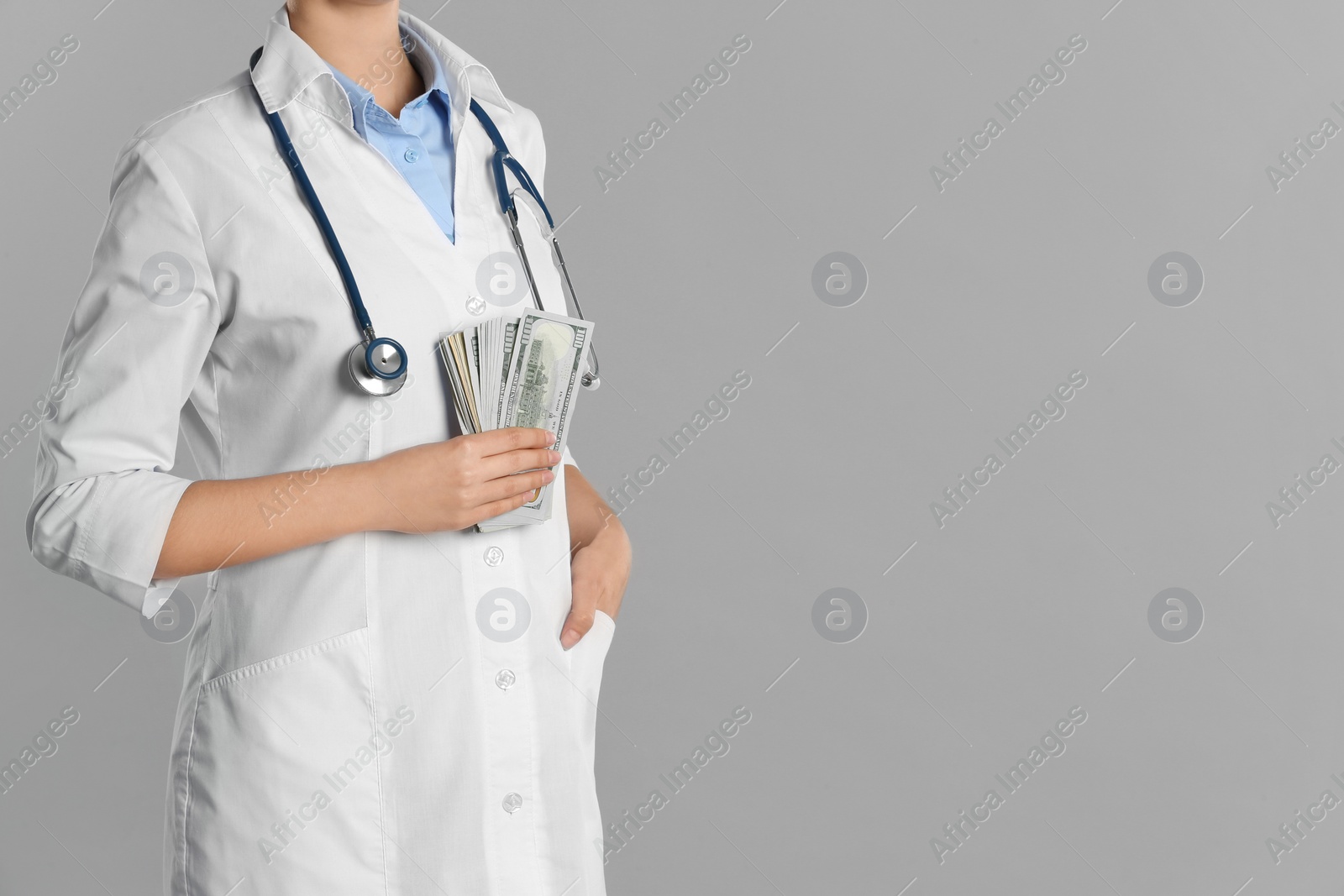 Photo of Doctor with bribe on grey background, closeup. Corruption in medicine