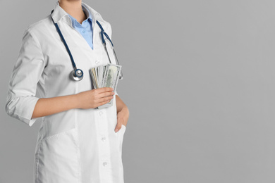 Photo of Doctor with bribe on grey background, closeup. Corruption in medicine