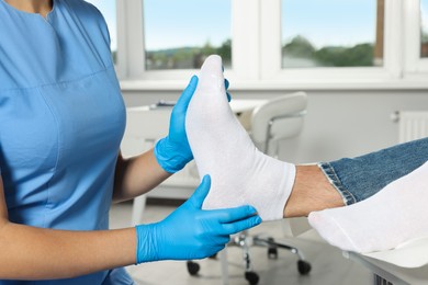 Photo of Female orthopedist examining patient's foot in hospital, closeup