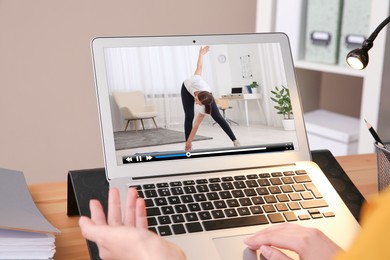 Image of Woman watching morning exercise video on laptop at table, closeup