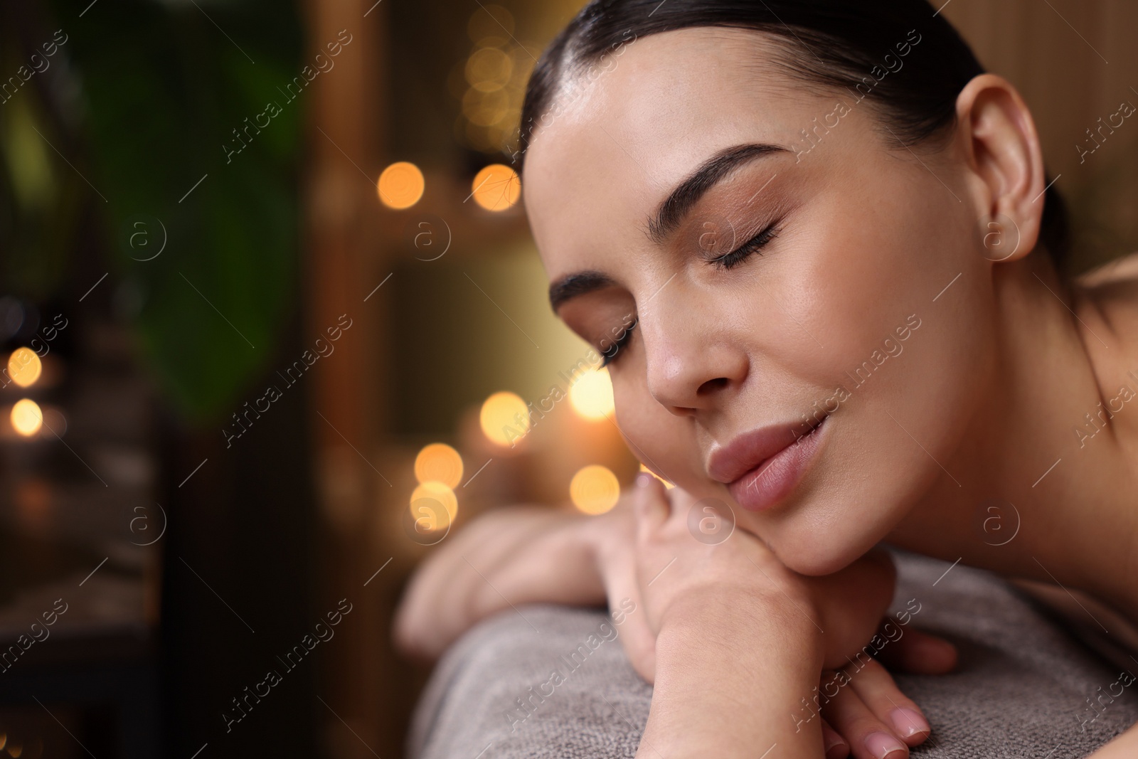 Photo of Spa therapy. Beautiful young woman lying on massage table in salon, space for text