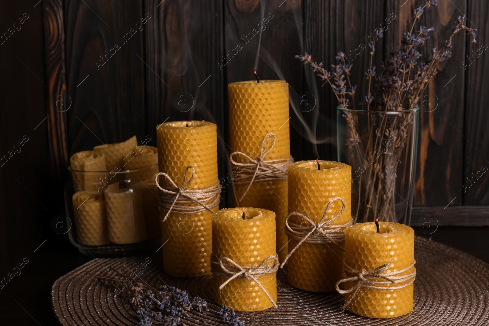 Photo of Beautiful beeswax candles and dried lavender flowers on table