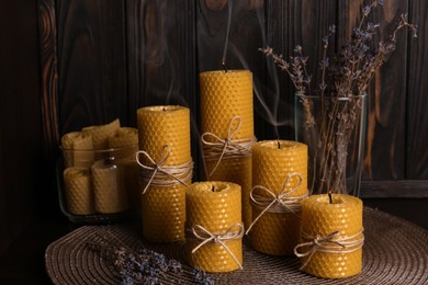 Photo of Beautiful beeswax candles and dried lavender flowers on table