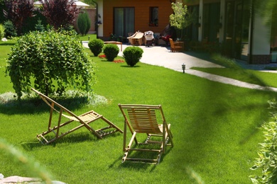 Wooden deck chairs in beautiful garden on sunny day