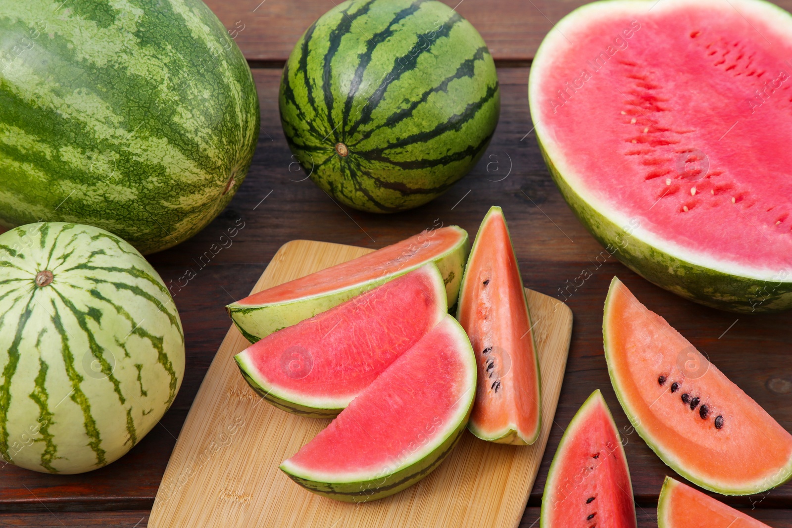 Photo of Different cut and whole ripe watermelons on wooden table, above view