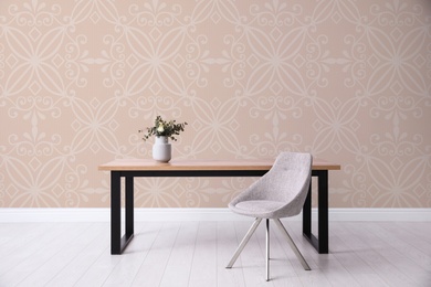 Image of Table and chair near patterned wallpapers. Interior design