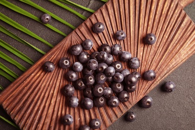 Photo of Fresh acai berries on wooden board, top view