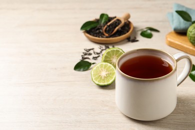 Photo of Cup of tasty bergamot tea on white wooden table, space for text