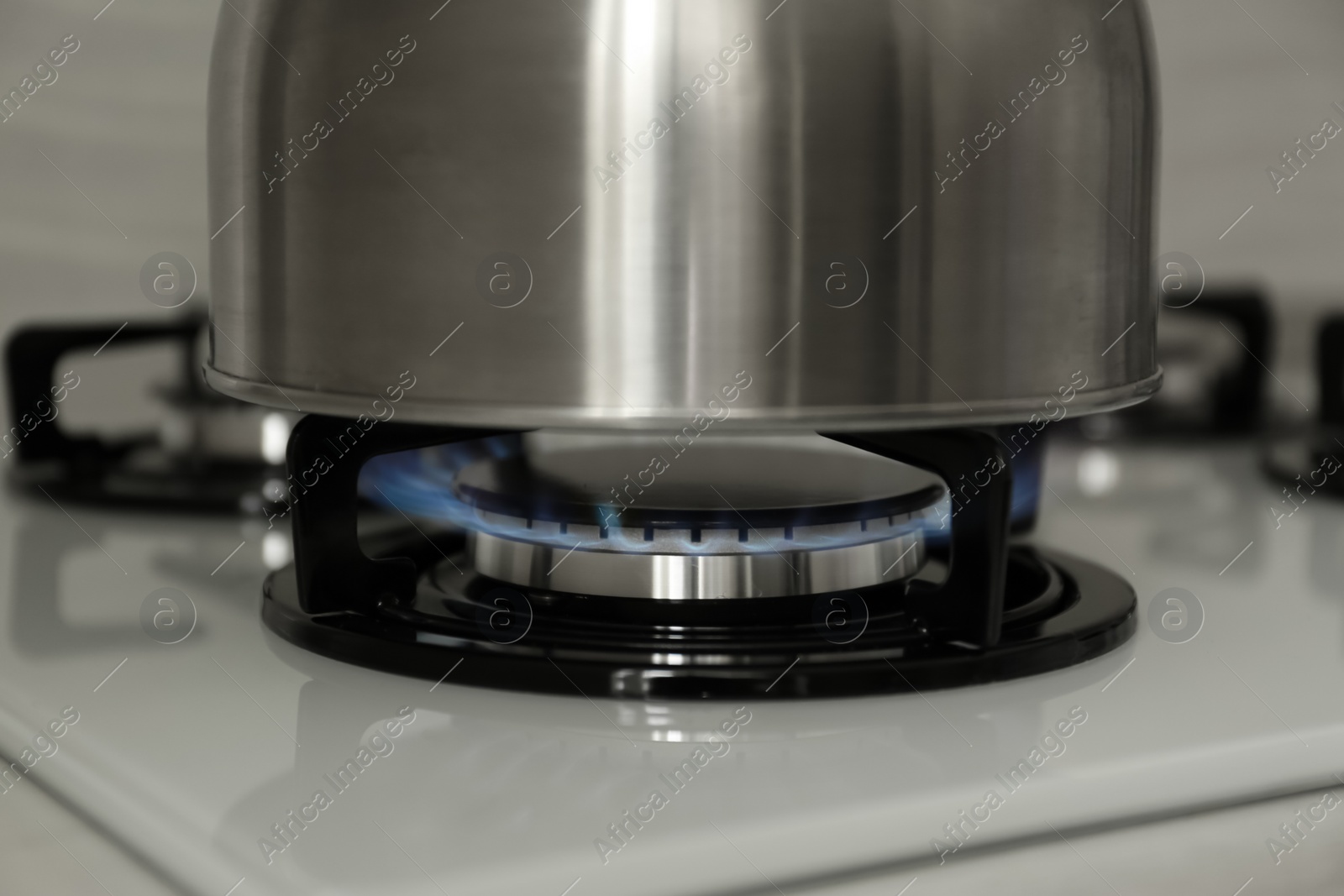 Photo of Steel kettle on modern gas stove, closeup