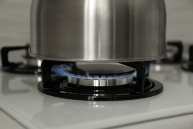 Photo of Steel kettle on modern gas stove, closeup