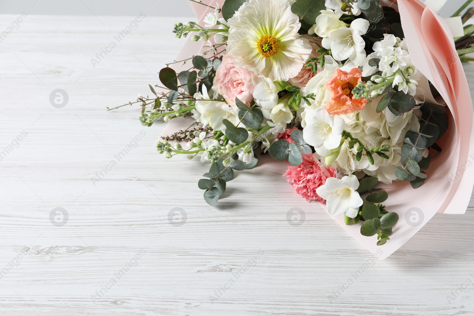 Photo of Bouquet of beautiful flowers on white wooden table. Space for text