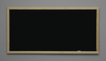 Clean black chalkboard hanging on grey wall