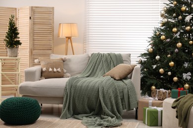Sofa near Christmas tree in room. Festive interior design