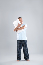 Man holding soft pillow on light background