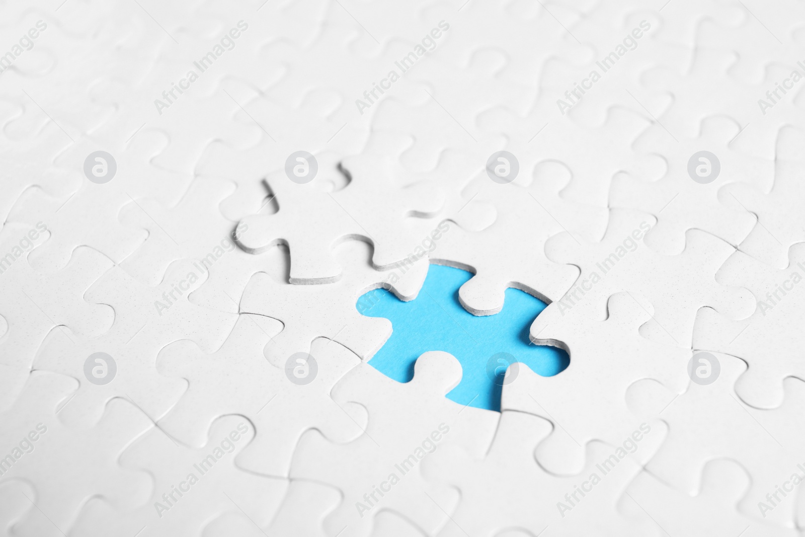 Photo of Blank white puzzle with separated piece on light blue background