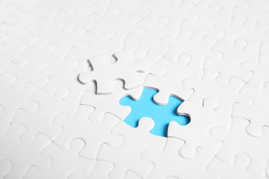 Photo of Blank white puzzle with separated piece on light blue background