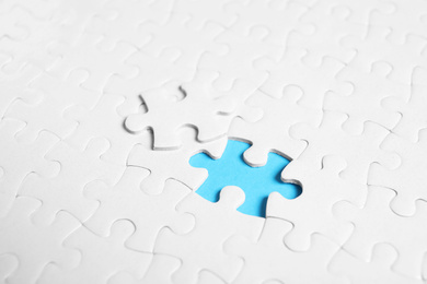 Blank white puzzle with separated piece on light blue background