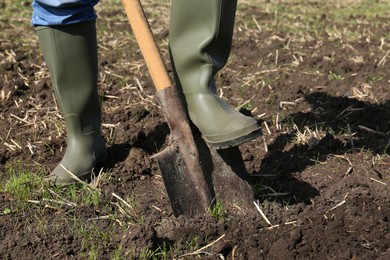 Photo of Man digging soil with shovel in field, closeup