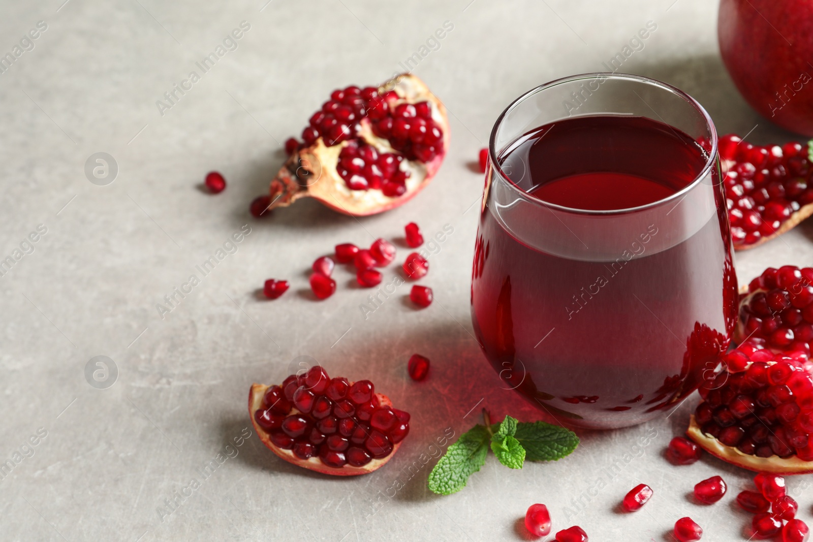 Photo of Composition with glass of fresh pomegranate juice on table. Space for text