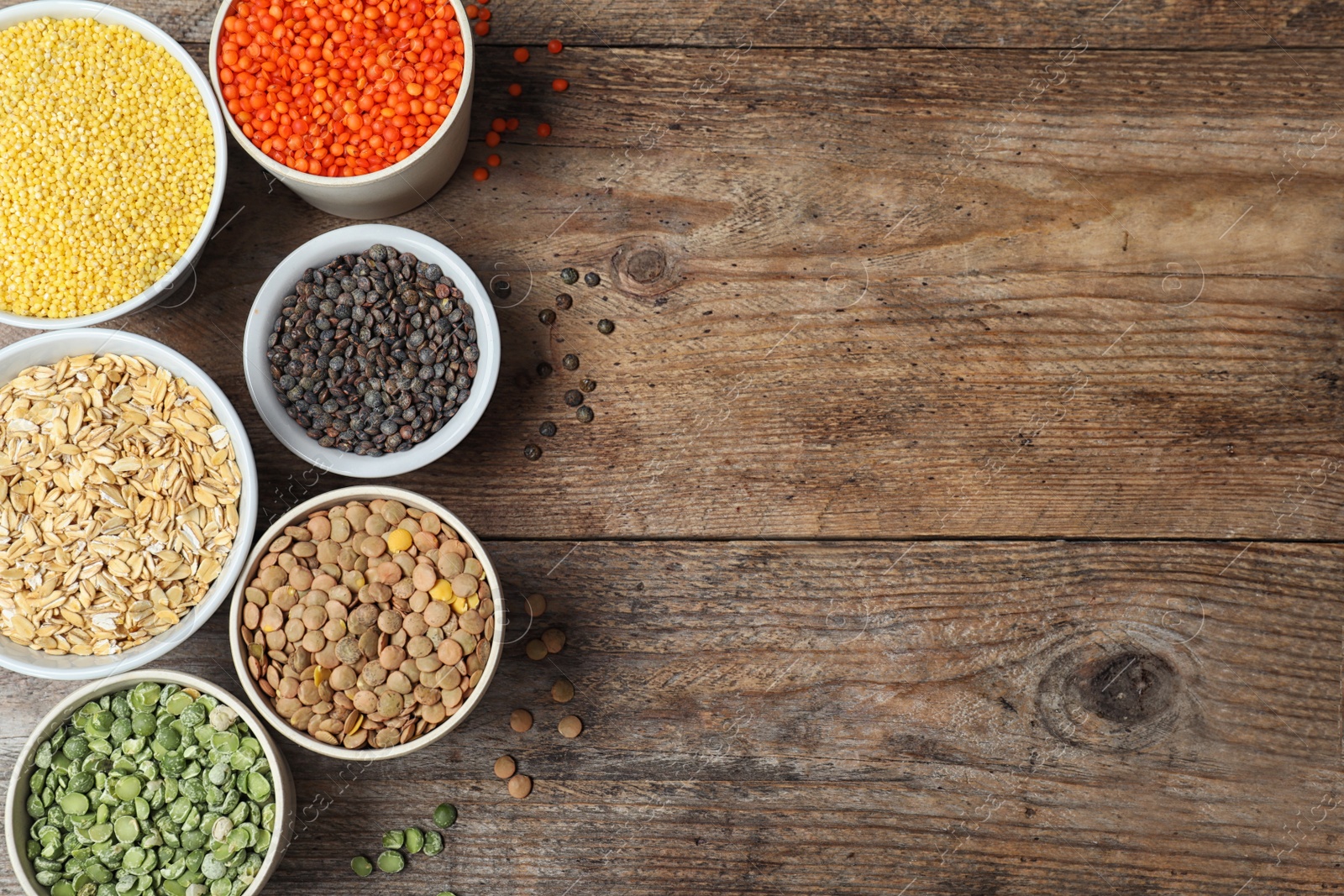 Photo of Flat lay composition with different types of legumes and cereals on wooden table, space for text. Organic grains