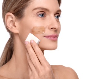 Photo of Woman applying foundation on face with makeup sponge against white background